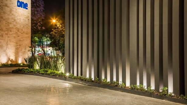 A modern building entrance with a 'one' sign, vertical light panels, and a well-lit pathway. - One Guadalajara Expo (Guadalajara)