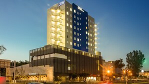 A multi-story hotel with a prominent 'One' sign, a ground-level restaurant, and a modern architectural design. - One Guadalajara Expo (Guadalajara)