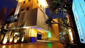 A modern hotel with a prominent entrance, a covered outdoor area with plants, and a sign indicating a natural theme. - Ease Motel (Caotun)