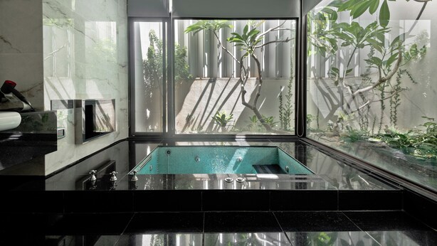 A modern bathroom with a glass-enclosed jacuzzi, marble walls, and a view of greenery outside. - Ease Motel (Caotun)