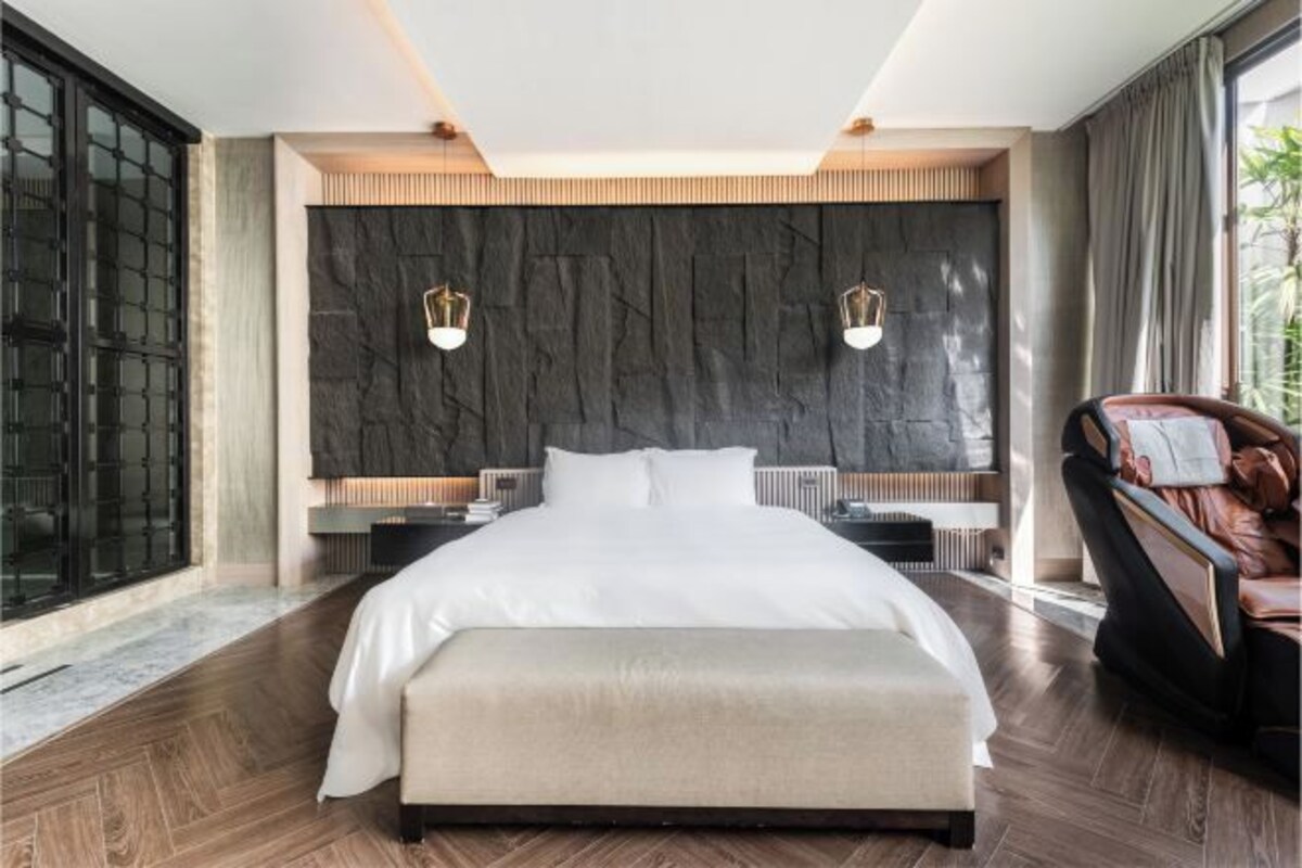 A modern bedroom with a large bed, a dark textured wall, and two bedside lamps.