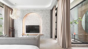 A modern bedroom with a large bed, a TV mounted on a stone wall, a small table with a vase, and a view of the outdoors through a glass window. - Ease Motel (Caotun)
