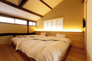A bedroom with a wooden bed, a large window with a view, and a ceiling with exposed beams.