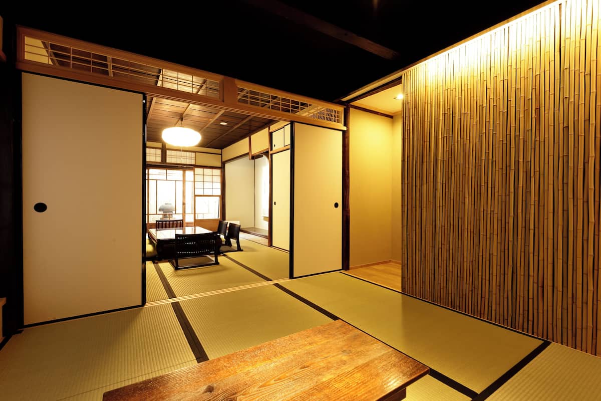 Ein traditioneller japanischer Raum mit Tatami-Böden, Schiebetüren und einem niedrigen Holztisch.