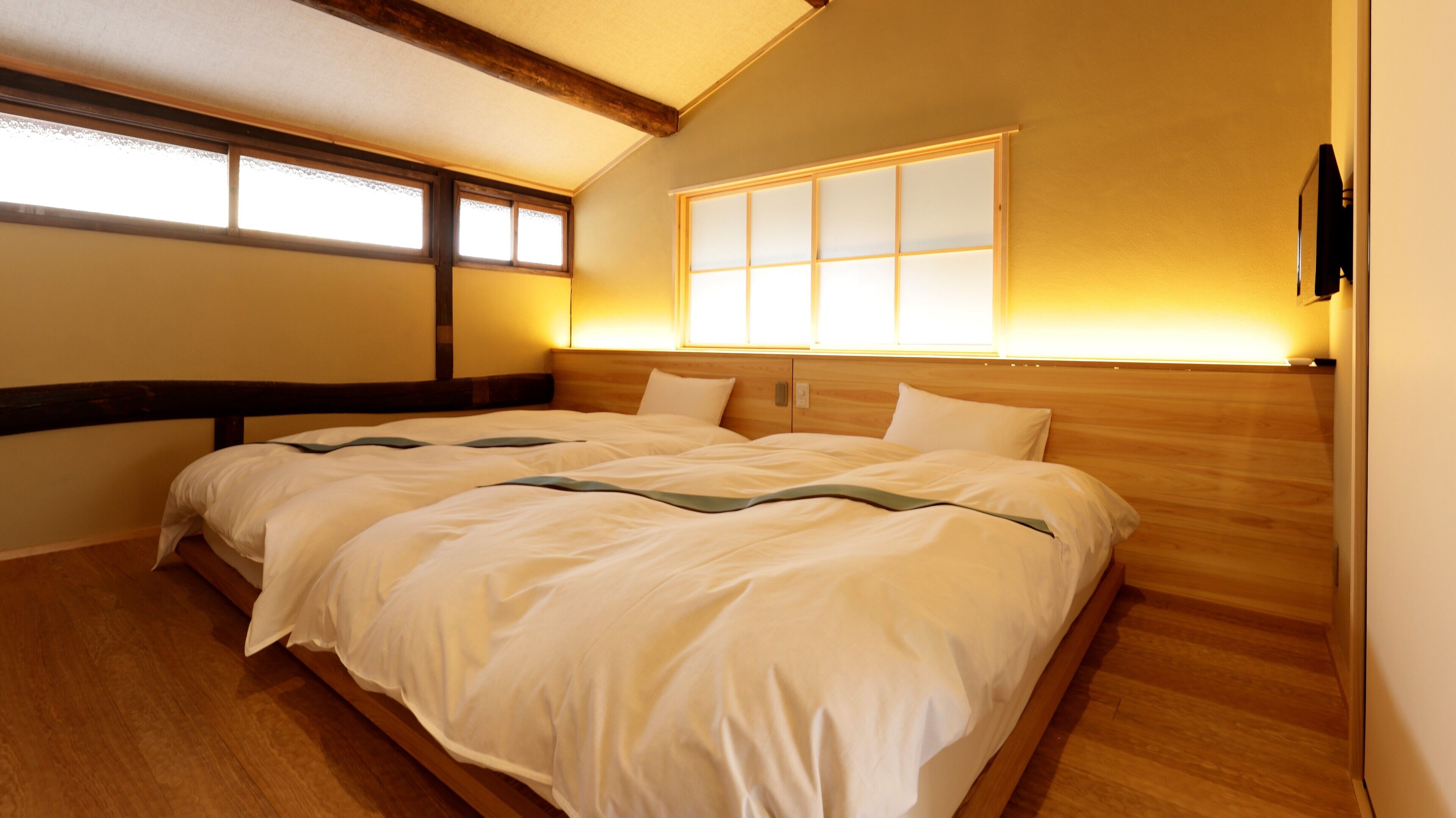 A bedroom with a large bed, wooden headboard, and a window with a view.