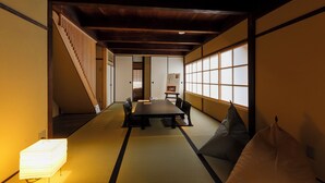 Een traditionele Japanse kamer met tatami vloerbedekking, een lage tafel en een bank.