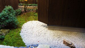 A garden with a wooden fence, a moss-covered ground, and a gravel path leading to a building. - Nakano-an (Kyoto)