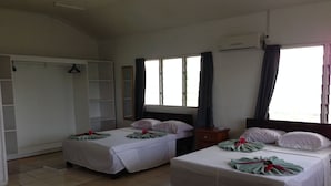 Habitación de hotel con dos camas, un armario, un espejo y una ventana con cortinas.