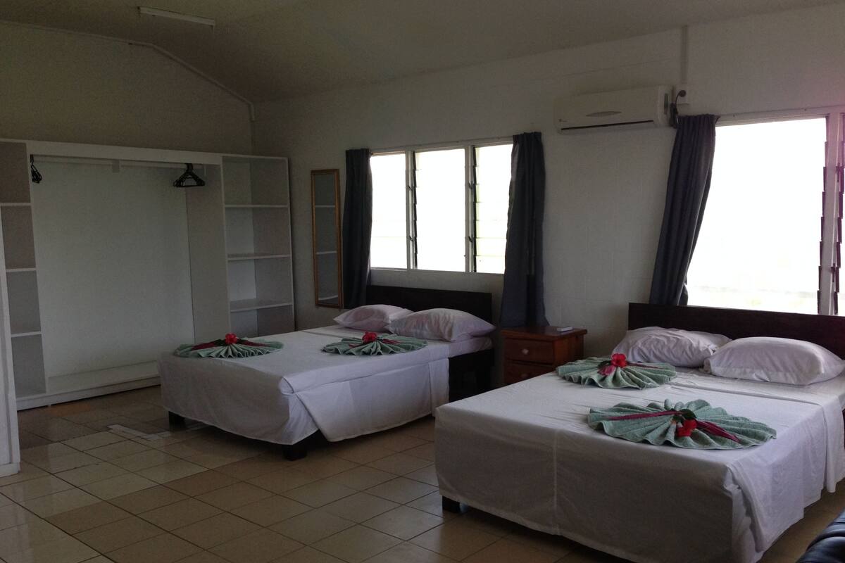 A hotel room with two beds, a wardrobe, a mirror, and a window with curtains.