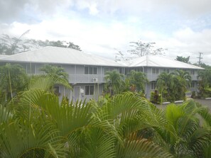 A two-story building with a flat roof, surrounded by lush greenery. - Samoa Sport Lodge (Apia)