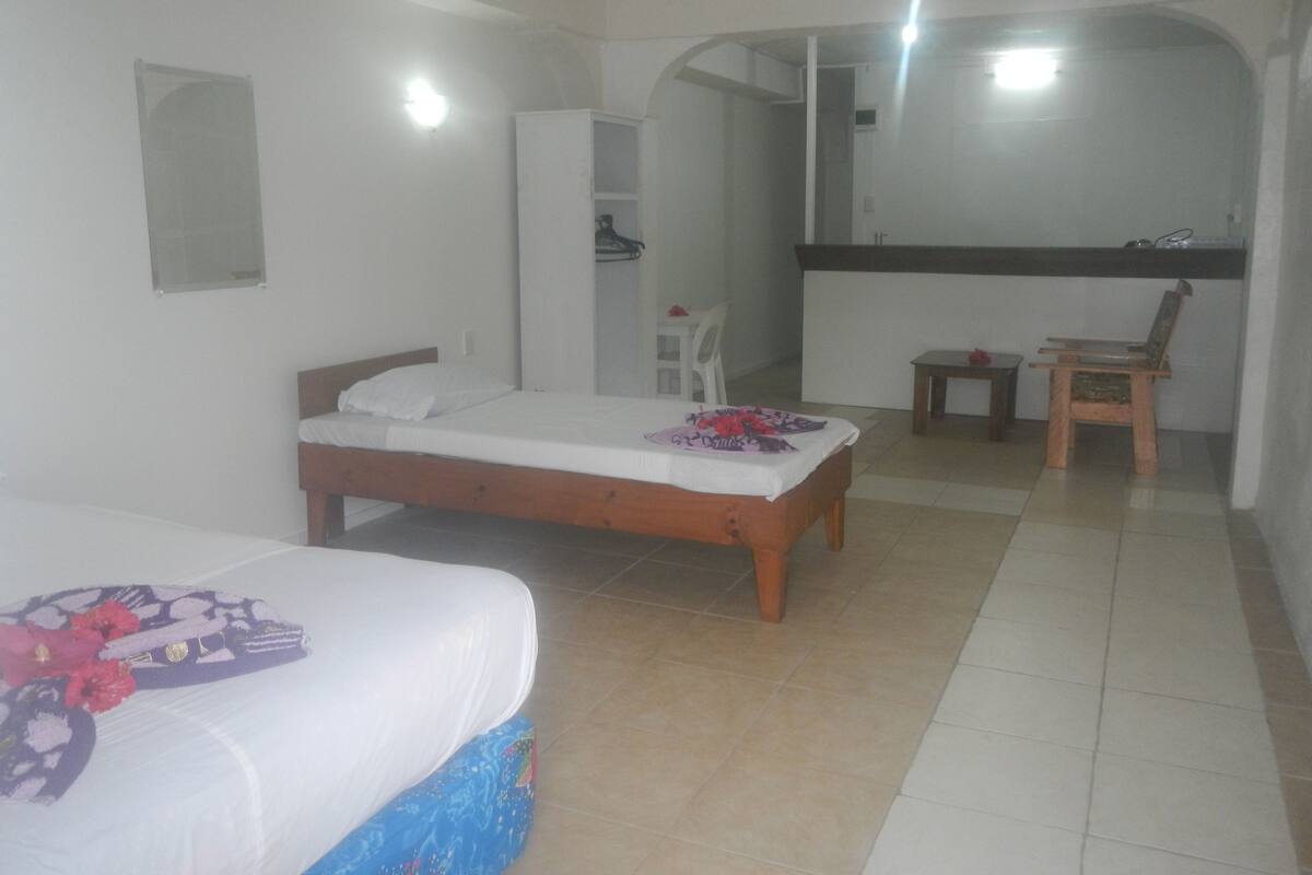 A bedroom with a bed, a chair, a small table, and a mirror.