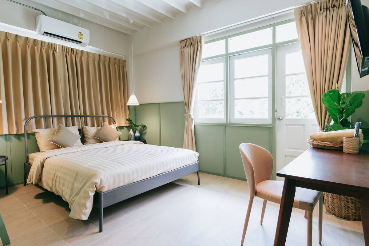 A bedroom with a bed, bedside table, lamp, and a window with curtains.