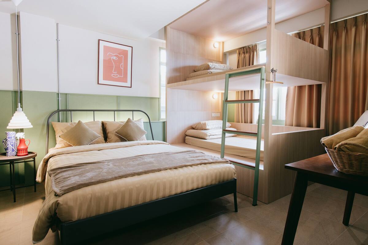 A hotel room with a bed, a nightstand, a lamp, a framed picture on the wall, and a window with curtains.