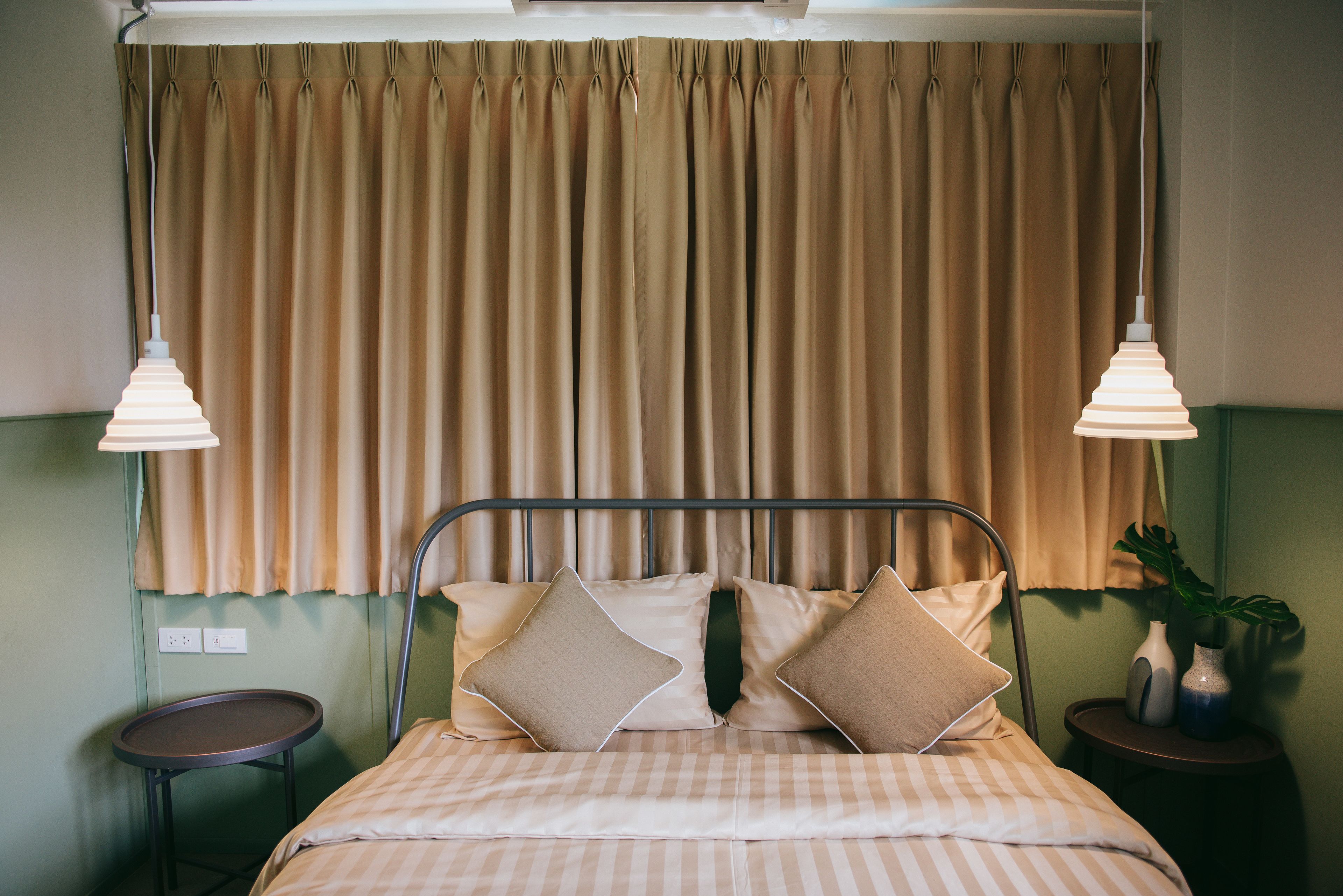 A neatly made bed with striped bedding, a metal headboard, and two bedside lamps.