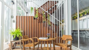 A wooden outdoor seating area with a herringbone floor pattern, surrounded by a white wall and a wooden fence. - Haus Hostel (Chiang Mai)