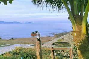 Uma praia com um poste de madeira, uma mesa pequena e um barco na água.