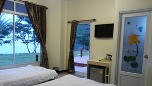 Habitación de hotel con dos camas, una kitchenette pequeña, un televisor y vista al mar.