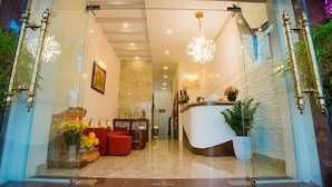 A reception area with a modern design, featuring a reception desk, seating area, and decorative lighting. - Smile Hotel (Hanoi)