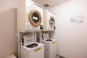 A laundry facility with two stacked washing machines and a dryer. - Hirosaki Plaza Hotel (Hirosaki)