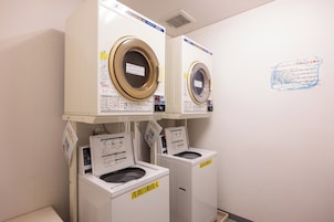 Un cuarto de lavandería con dos lavadoras apiladas y una secadora.