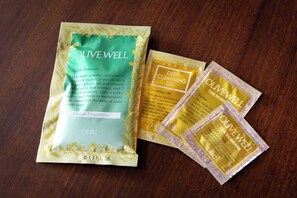 Drie verpakkingen Olive Well badproducten op een houten ondergrond.