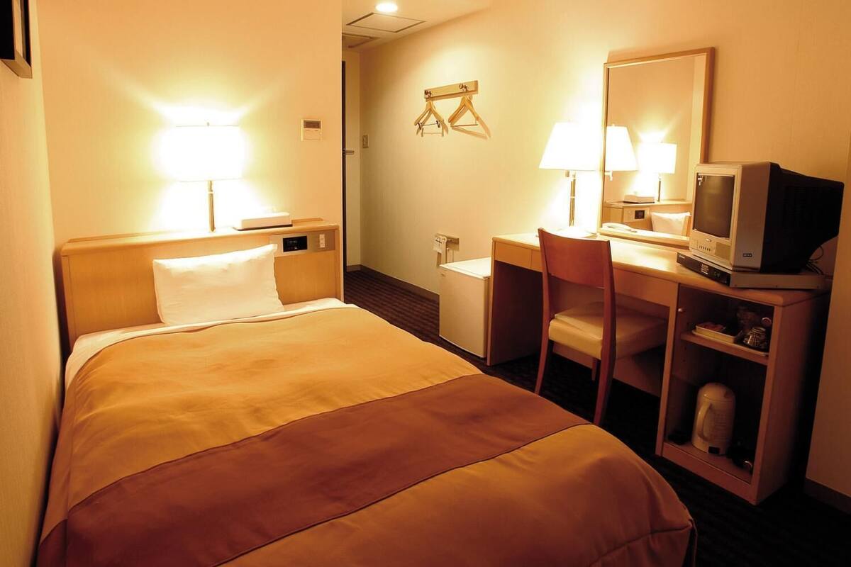 Une chambre d’hôtel équipée d’un lit, d’un bureau, d’une chaise et d’un téléviseur.