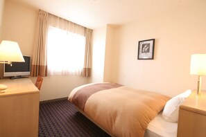 Une chambre d’hôtel avec un lit, un bureau avec une lampe, une télévision et une fenêtre avec des rideaux.