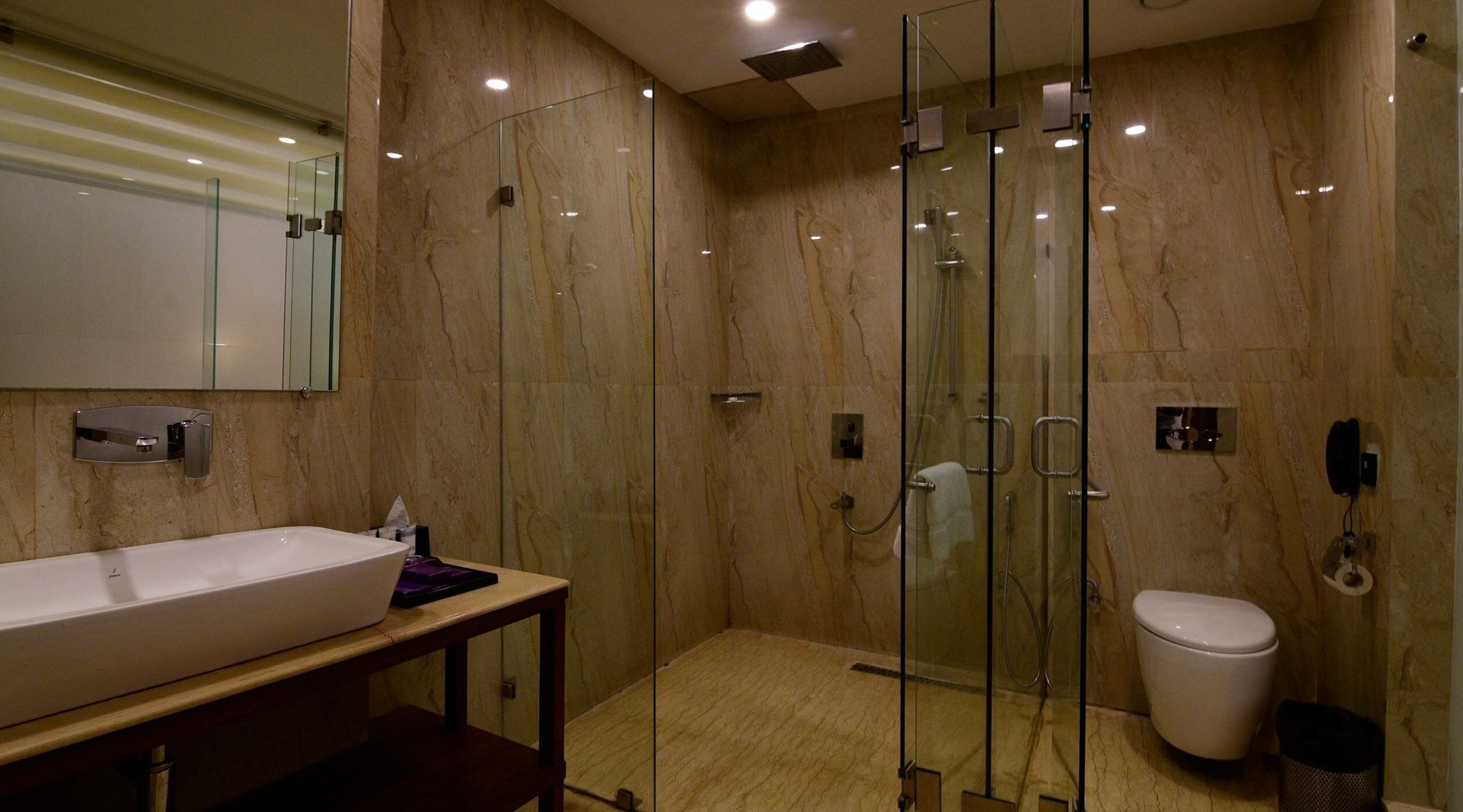 A modern bathroom with a glass-enclosed shower, a white sink, and a toilet.