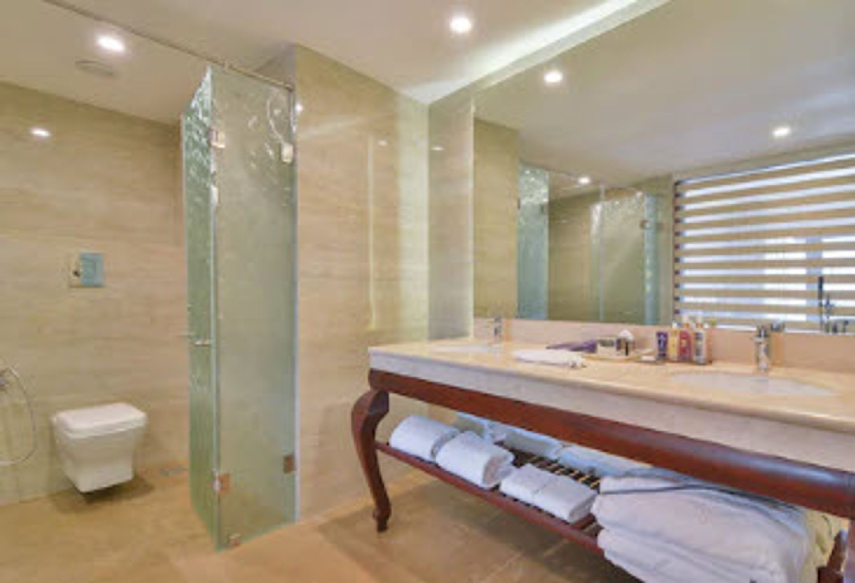 A bathroom with a glass shower enclosure, a wooden vanity with a mirror, and a towel rack.