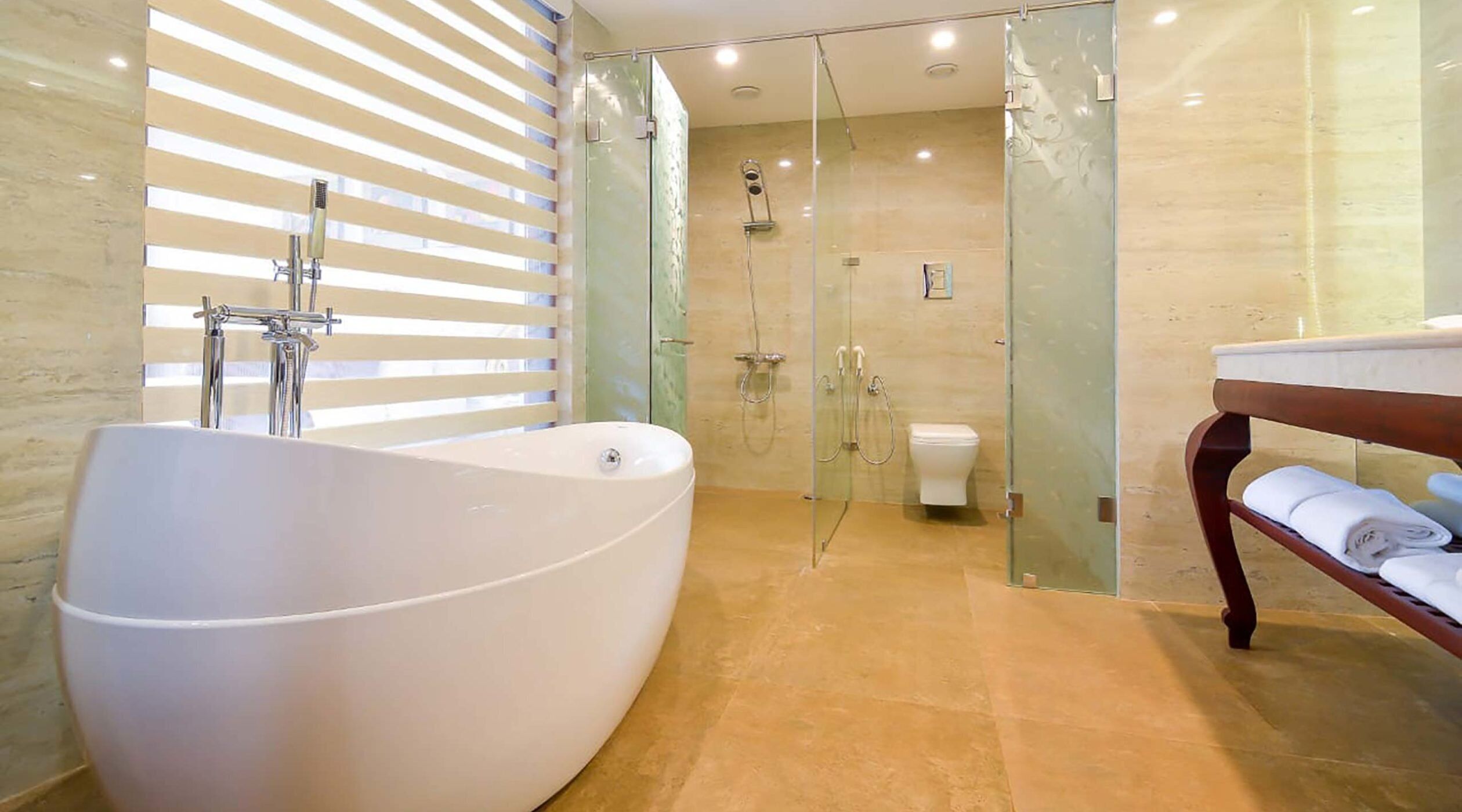 Un baño moderno con una bañera independiente, ducha con cerramiento de vidrio y tocador de madera con toallas.