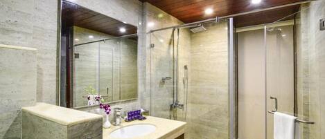 A modern bathroom with a marble vanity, a large mirror, a glass shower enclosure, and a wooden ceiling.