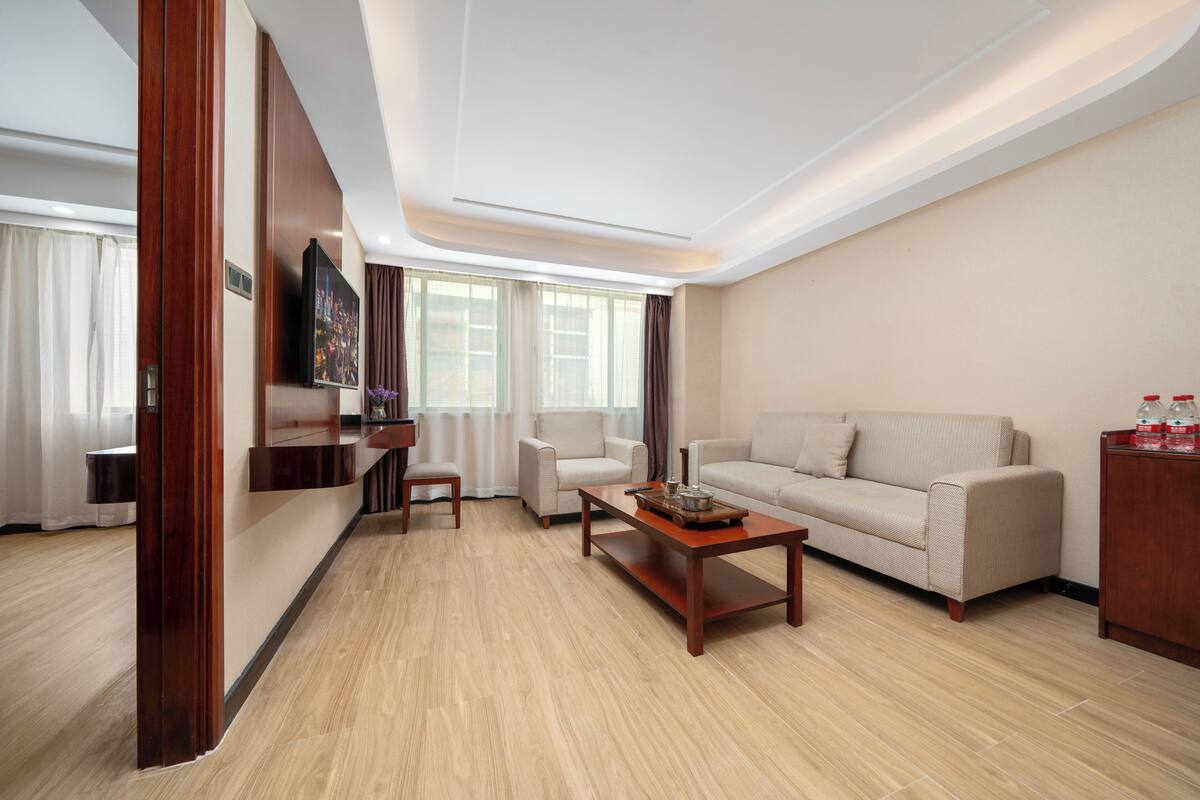 Uma sala de estar moderna com sofá, duas poltronas, uma mesa de centro e uma TV fixada na parede.