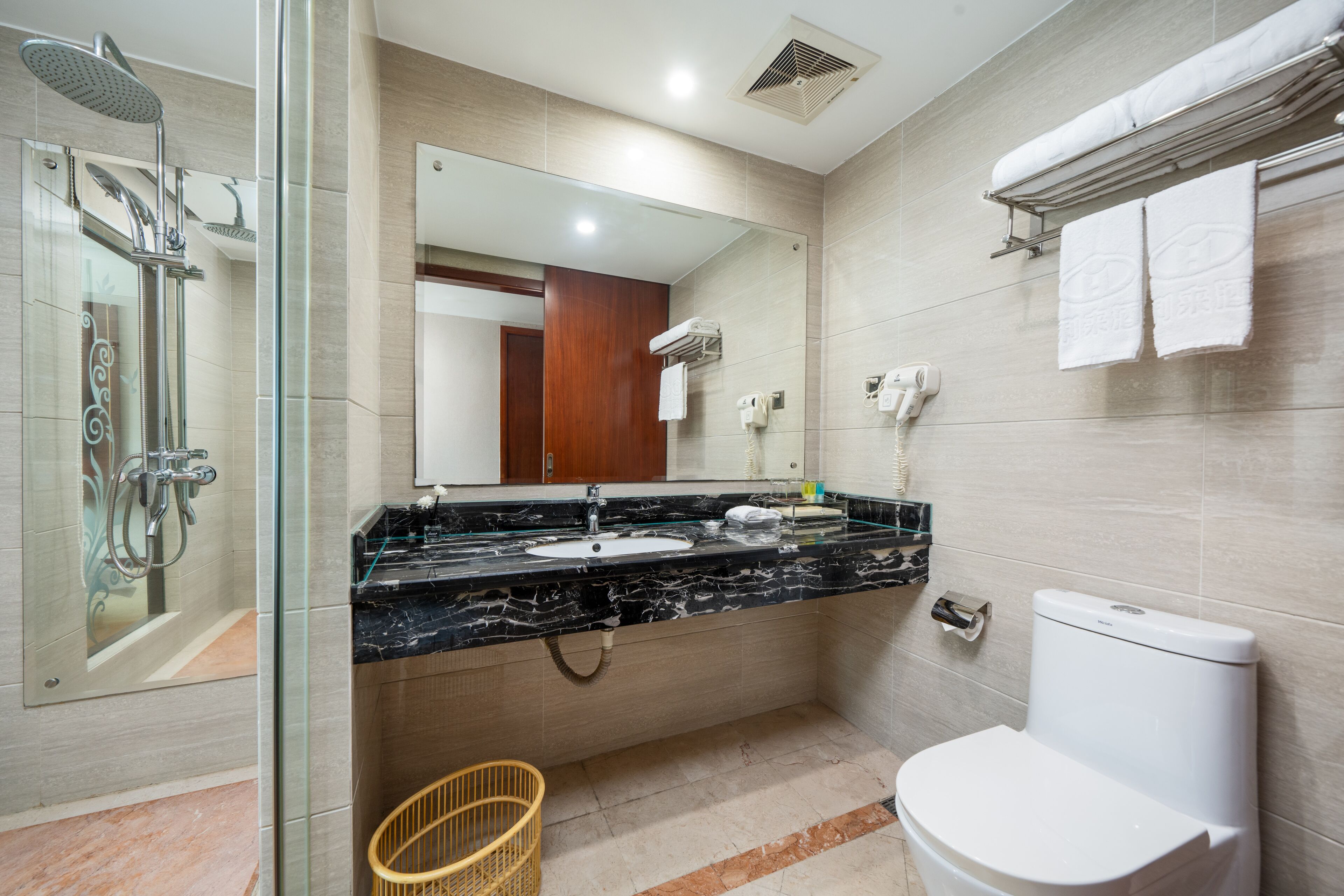 Une salle de bain moderne avec une douche à parois de verre, un lavabo en marbre, des toilettes et un miroir.