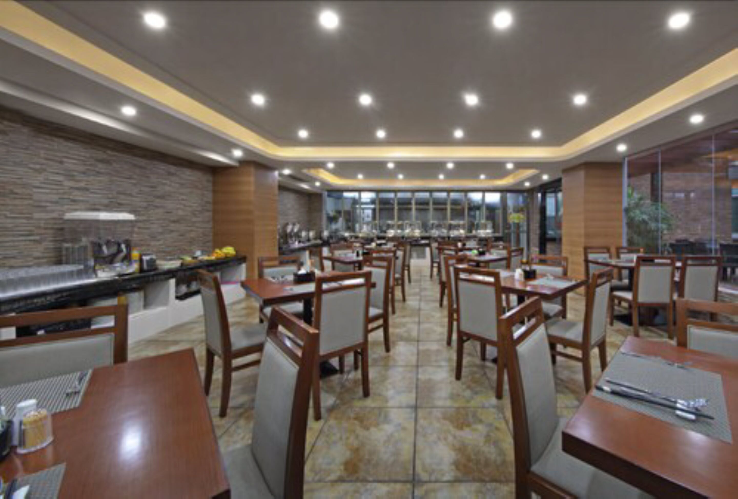 Un restaurant spacieux, doté de nombreuses tables et chaises, d’un espace buffet et d’un mur en pierre.