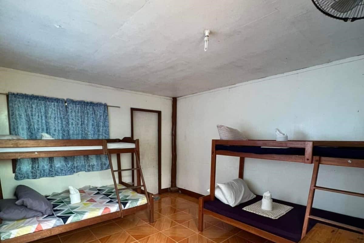 A room with two bunk beds, a wooden table, and a ceiling fan.