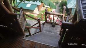 A wooden staircase with a railing leading to a covered outdoor area with potted plants and flowers. - Floresita's Beach Resort (El Nido)