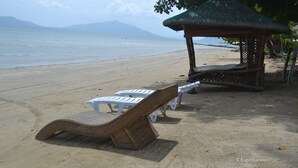 A beach with lounge chairs and a thatched-roof gazebo. - Floresita's Beach Resort (El Nido)