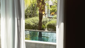 Ein Schlafzimmer mit Blick auf einen Swimmingpool und Palmen.