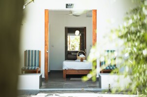 Una habitación con una cama, una silla, una puerta de madera y un ventilador de techo.
