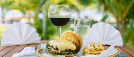 A meal with a burger, fries, and a glass of wine on a wooden table.