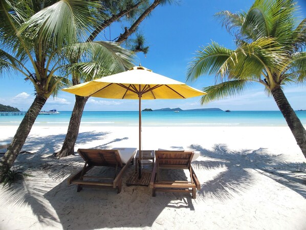 On the beach, white sand, sun-loungers, beach umbrellas