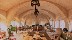 A spacious room with a long wooden table, chairs, and a hanging light fixture. - Kistar Cave Hotel (Nevsehir)