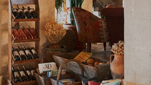 A cozy interior with a wine rack, a wicker basket, and a rustic chair. - Kistar Cave Hotel (Nevsehir)