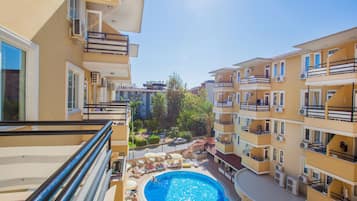 A residential building with a swimming pool, balconies, and air conditioning units.
