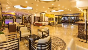 A hotel lobby with a restaurant, reception desk, and seating area. - Kleopatra Ada Hotel - All Inclusive (Alanya)