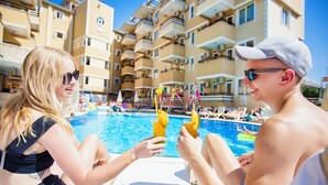A poolside scene with a building in the background. - Kleopatra Ada Hotel - All Inclusive (Alanya)