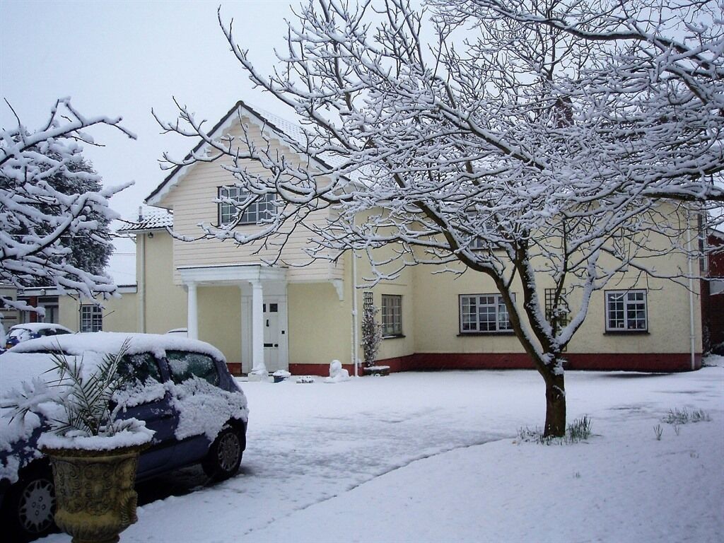 A house with a snow-covered driveway and a parked car.