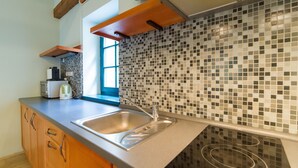 A modern kitchen with a large island, a built-in stove, and a tiled backsplash. - Apartmány U Zvonu (Cesky Krumlov)