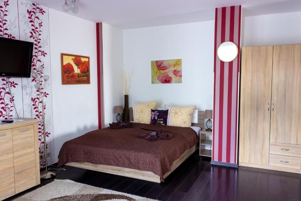 Un dormitorio con una cama, un televisor, un armario y dos cuadros en la pared.
