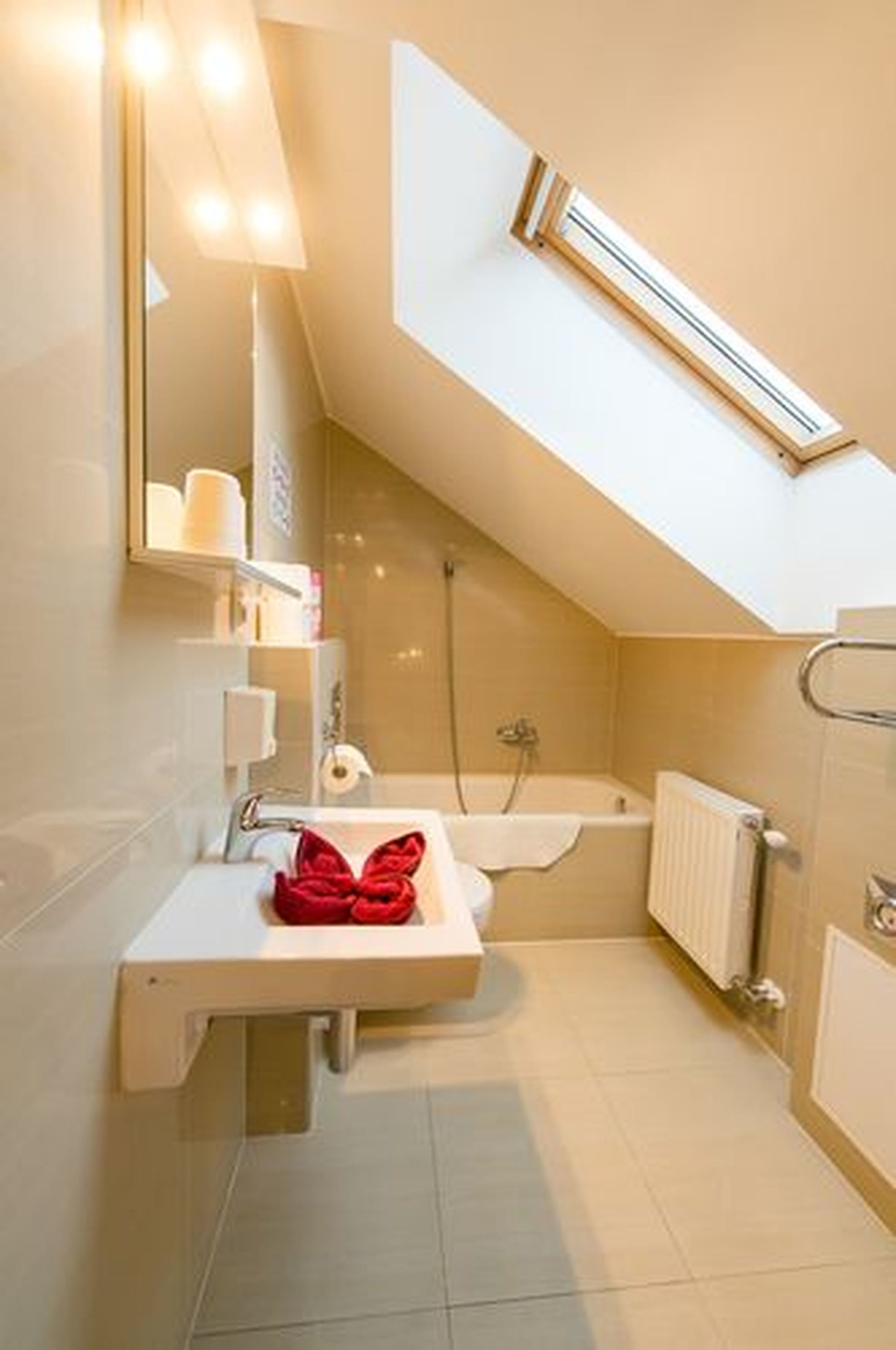 Ein modernes Badezimmer mit Dachfenster, einer Badewanne und einem Waschbecken mit Handtuch.